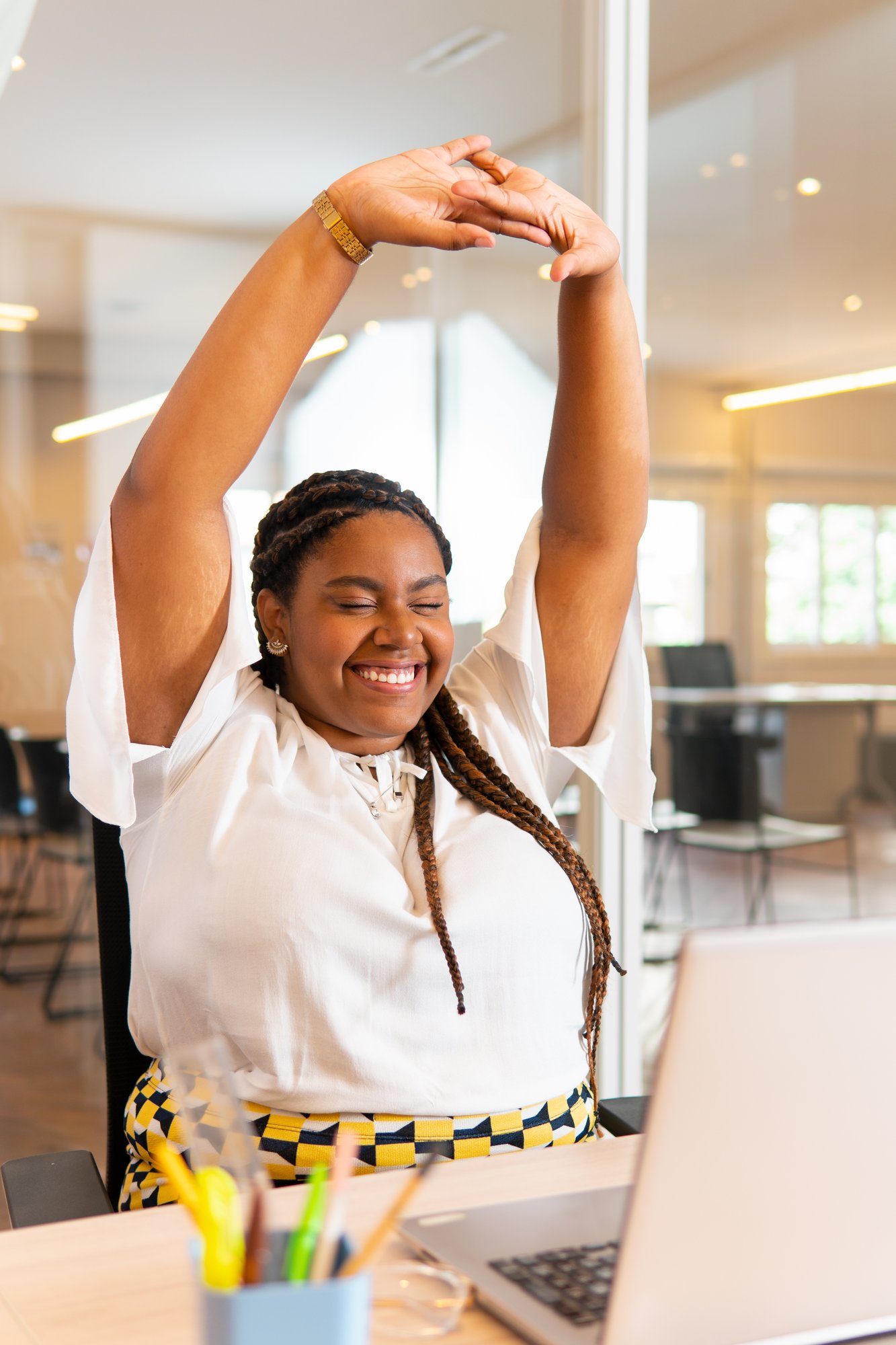 Woman stretching and smiling at a work space in front of a computer