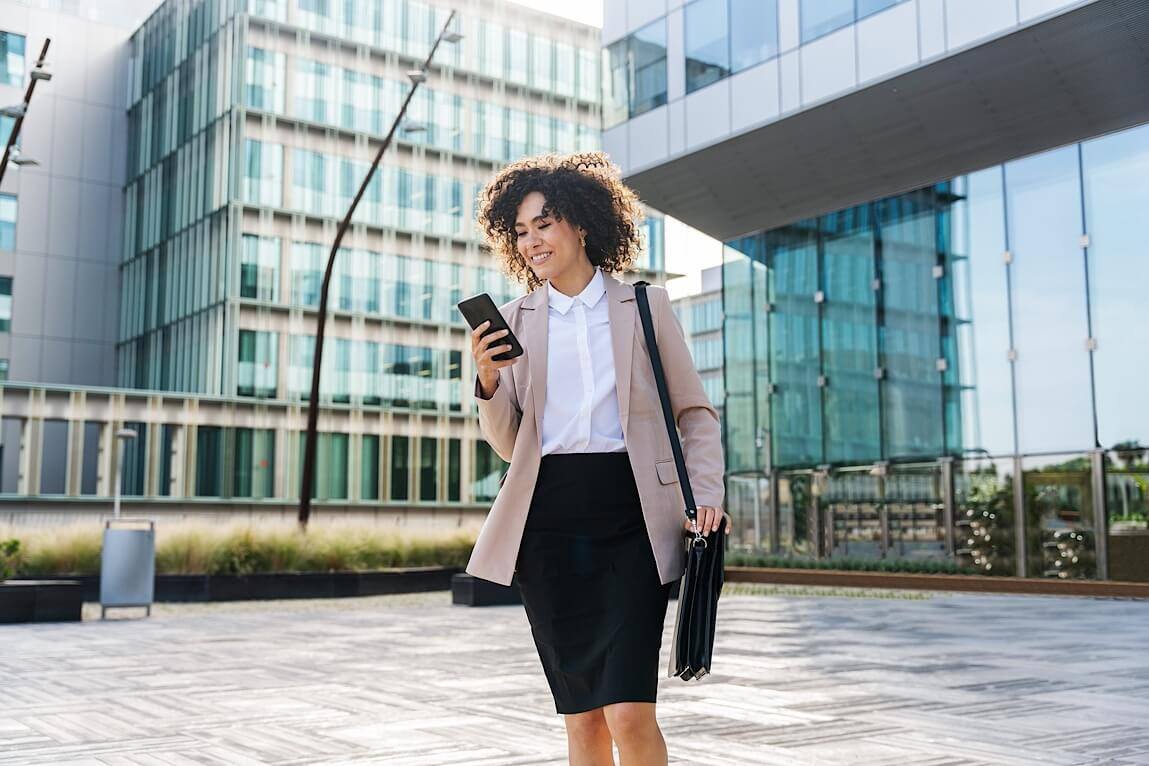 Businesswoman walking and using smartphone